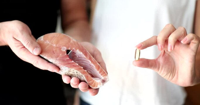 People hold a portion of salmon and vitamin D capsule, closeup. Vitamins in sea fish, fresh orange steak