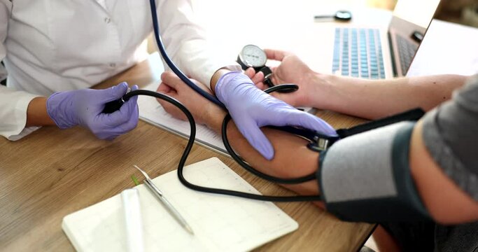 The doctor in the clinic measures a person pressure, hands close-up. Medical equipment for monitoring blood pressure