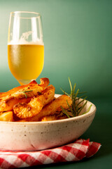 Delicious Fried Cassava in Handcrafted White Ceramic Bowl on Green Studio Background with cold beer