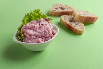 A bowl tarama or taramasalata and several toasts on the light green background