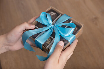 Gift box with chocolate craft candies in boys hands. Sweet gift box