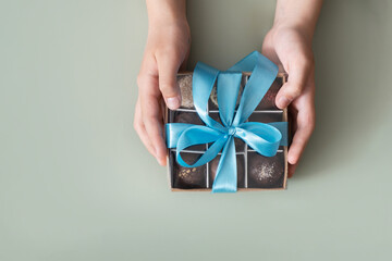 Gift box with chocolate craft candies in boys hands. Sweet gift box