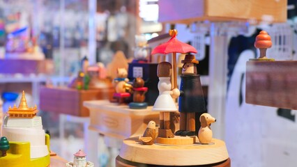 Wooden music box is spinning in a display case. Close up wooden people under an umbrella are spinning on a music box. Concept buy a music box with wooden people for a child and make him happy.