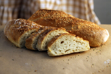 Bread, traditional sourdough bread, sliced on a rustic wooden background. French baguette with sesame seeds. Concept of traditional yeast bread baking methods. Healthy eating. Breakfast bread. 