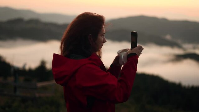 Pretty young woman hiker taking photos saving great memories on smartphone mobile phone at beautiful sunset in mountains Pretty girl create content for social media outdoors High quality 4k footage