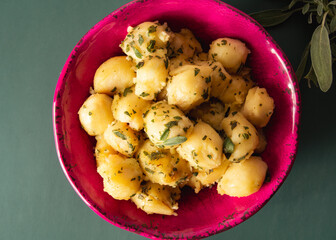Top view Delicious Fried Gnocci with sage butter in a pink bowl and a red blackground