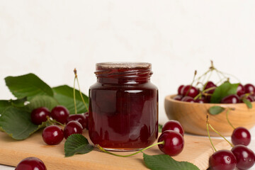 Jar with tasty homemade cherry jam on wooden table