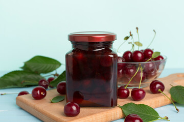 Jar with tasty homemade cherry jam on wooden table
