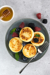 Cottage cheese pancakes, syrniki with honey, berries on blue background. Top view. Russian, ukrainian food