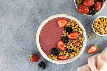 Smoothie bowl with strawberries, blackberries and granola on a blue background. Healthy breakfast. Top view. Copy Space.