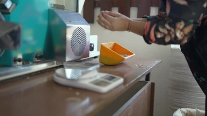 Agronomist measuring rice on quality checking device in mill production plant, slow motion