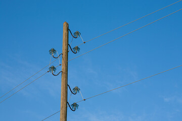 A wooden electric pole, on a blue background with the moon in the background