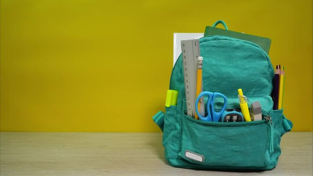 Full of school accessories schoolbag on the desk. Animation of opening backpack with school items. Back to school concept