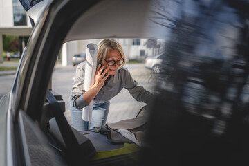 mature blonde woman travel take stuff belongings from the back of car