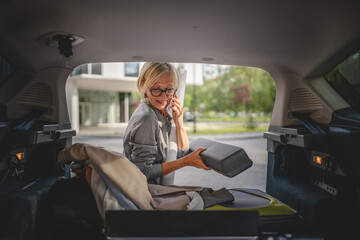 mature blonde woman travel take stuff belongings from the back of car