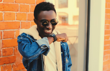Portrait of stylish happy smiling african man with smart watch using voice command recorder or...