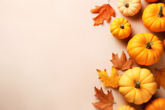 Orange pumpkins and autumn leaves on beige background