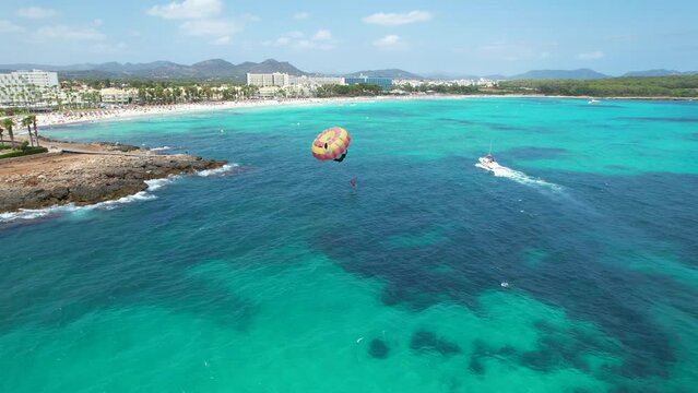 Aerial view of tourists enjoying parasailing in Sa Coma beach in Mallorca, Spain on a summer day