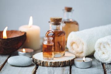 Obraz na płótnie Canvas Concept of spa treatment in salon with pure organic natural oil. Atmosphere of relax, detention. Aromatherapy, candles, towel, wooden background. Skin care, body gentle treatment