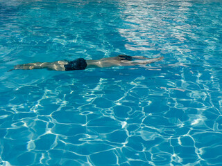 young boy swimming in the pool , moving under the water in the pool