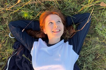 portrait of a young woman lying on the grass in the summer warm weather at sunset
