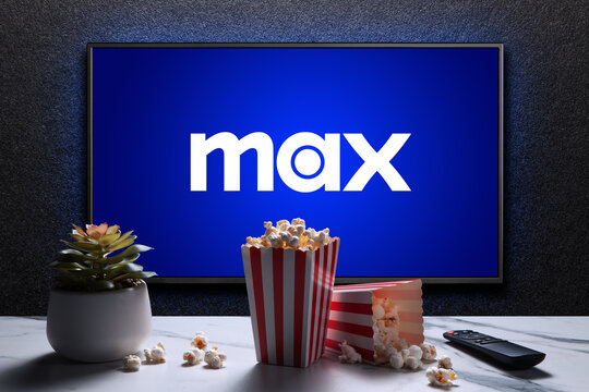 Max or HBO Max logo on TV with popcorn boxes, reomote control and home plant on the table. HBO Max is an American subscription video on-demand streaming service. Astana, Kazakhstan - July 21, 2023.
