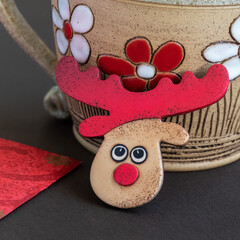 Reindeer brooch from polymer clay leaning on mug with floral pattern