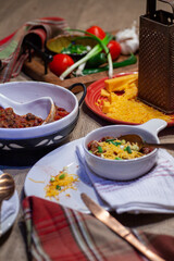 Homemade chili dinner with cornbread and ingredients.