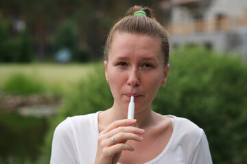 Beautiful girl, young woman is smoking, modern hybrid electronic cigarette device, technology,...