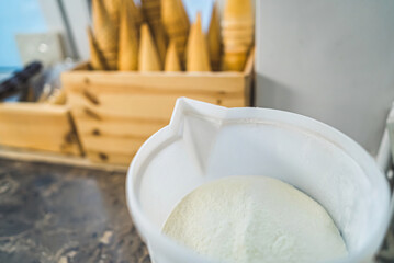 Delicious vanilla ice cream in big bucket ready to fill ice cream cons. Closeup shot of ice cream production process. Confectionery kitchen background. . High quality photo