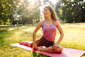 Portrait of a beautiful woman doing yoga in the park. Young curly woman in sportswear goes in for sports. Active lifestyle. Fitness, sports.