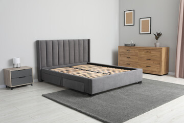 Comfortable bed with storage space for bedding under slatted base in stylish room - obrazy, fototapety, plakaty