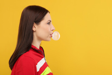 Beautiful woman blowing bubble gum on orange background, space for text