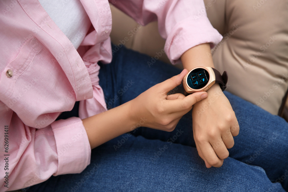 Poster woman setting smart home control system via smartwatch indoors, closeup. app interface with icons on