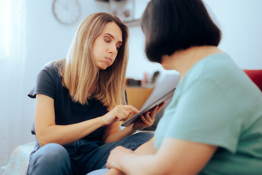 Woman Showing her Elderly Relative how to Use a Tablet. Person trying to prevent scam happening to an senior woman
