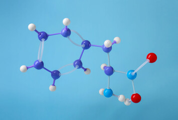 Molecule of phenylalanine on light blue background. Chemical model