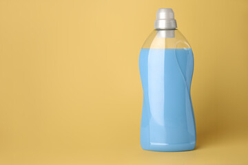 Bottle of fabric softener on pale yellow background, space for text