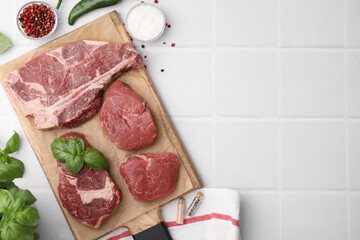 Flat lay composition with cut fresh beef meat and spices on white tiled table, flat lay. Space for text