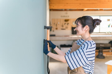 Fototapeta na wymiar ガレージに釘を打つ日本人女性（リノベーション・DIY） 