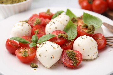Tasty salad Caprese with tomatoes, mozzarella balls and basil on plate, closeup