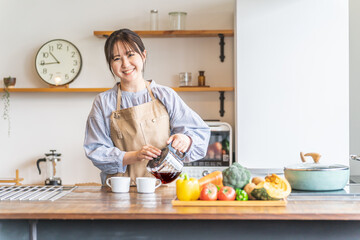 朝キッチンでコーヒーを淹れるエプロン姿のアジア人女性
