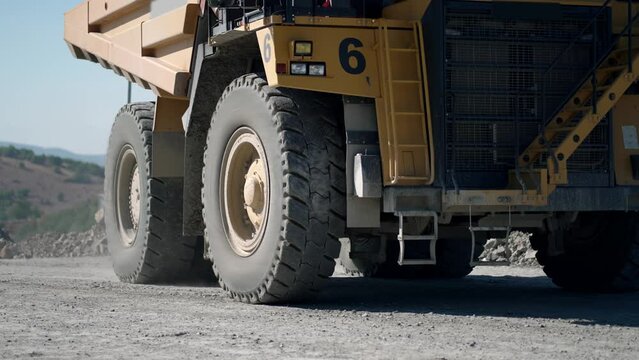 Large quarry dump truck transporting ore on open pit mine, slow motion