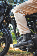 Obraz premium Bottom view of young man wearing leather boots and brown corduroy jeans riding a motorcycle