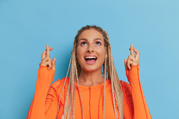 Close-up shot of pretty woman wearing orange longsleeve top on blue background, smiling and...