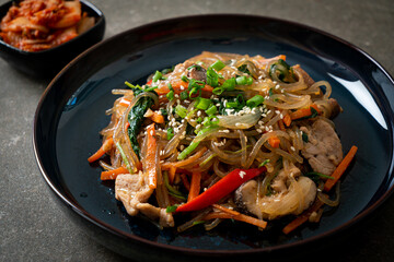 japchae or stir-fried Korean vermicelli noodles with vegetables and pork topped with white sesame