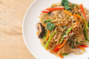 japchae or stir-fried Korean vermicelli noodles with vegetables and pork topped with white sesame