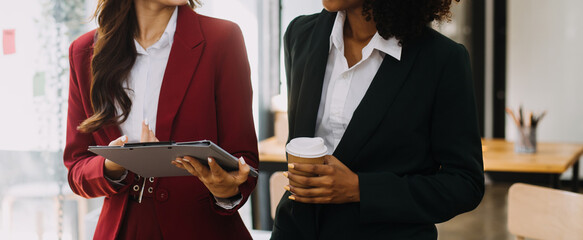 Entrepreneur Asian businessman and businesswoman discussing new business project in tablet in modern Meeting In Modern Office, Asian business casual concept.