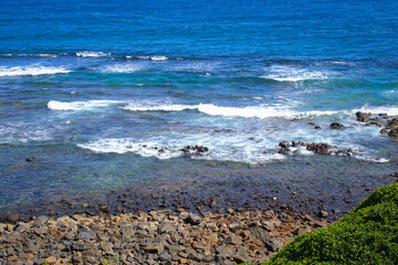 Fototapeta na wymiar Sunny day at the beach, blue sea, waves and stones