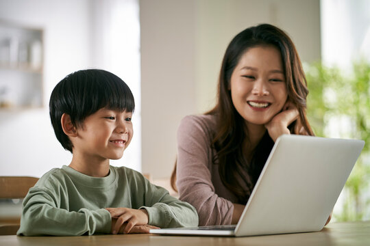 asian mother and son using laptop computer together at home