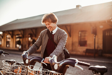 Mature man picking up a bicycle from the public bicycle sharing station in the city